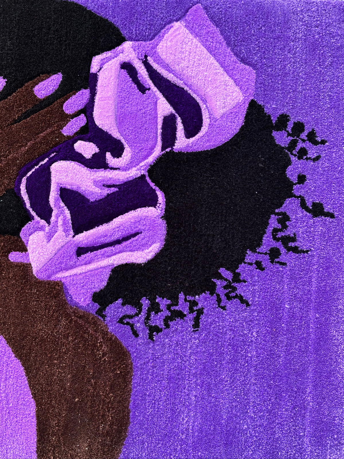 A close-up of a textured rug featuring an abstract portrait of a person in purple, black, and brown tones.